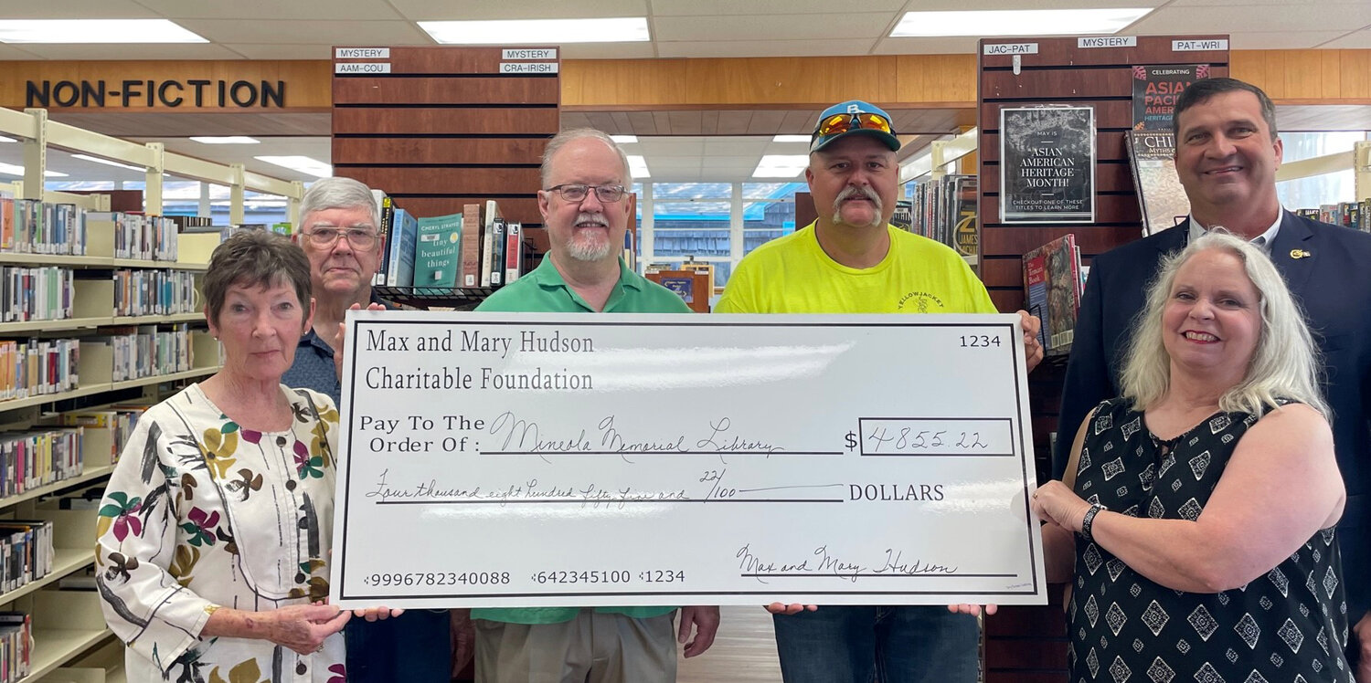 Mineola Memorial Library board chairman Lou Steel, left, and librarian Mary Hurley, right, show off the check from the Hudson Foundation. Foundation committee members, from left, are Mike Ferguson, Jimmy Phillips and Robbie Ballard and Edward Jones advisor Leon Anderson.